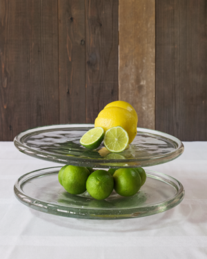 Two-tiered glass plate serving tray with lemons and limes.